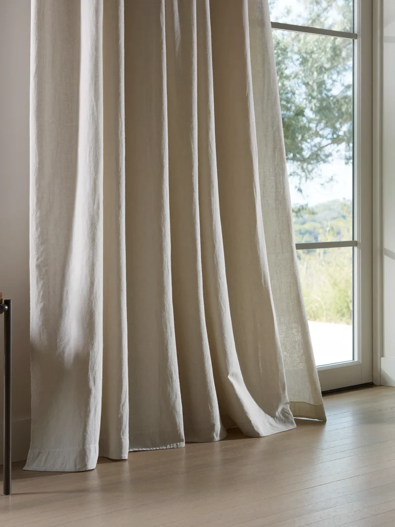 Bodenlange Leinenvorhänge am hohen Fenster mit weichem Tageslicht